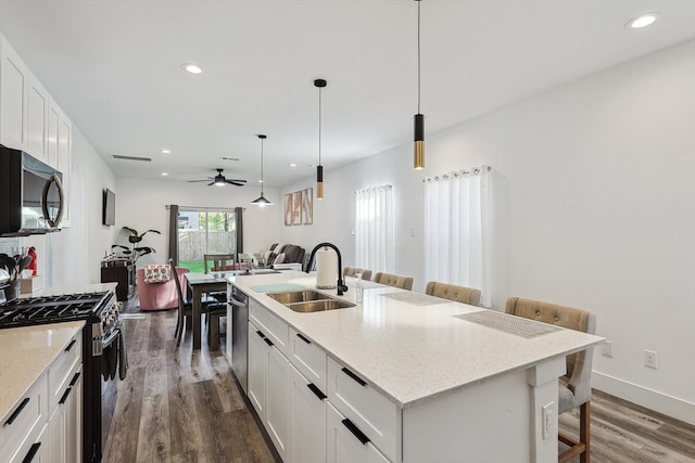 kitchen featuring a kitchen breakfast bar, a center island with sink, sink, white cabinets, and appliances with stainless steel finishes