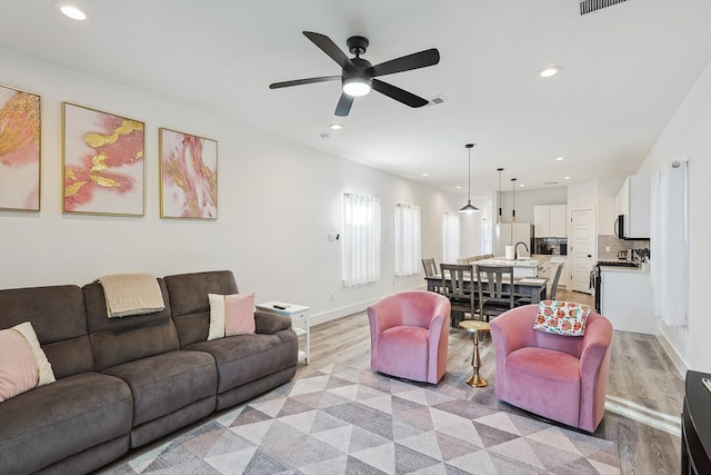 living room featuring light hardwood / wood-style floors and ceiling fan