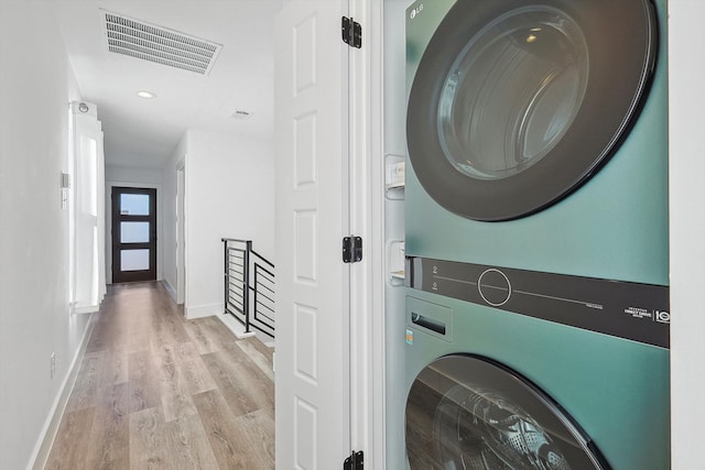 laundry room with light hardwood / wood-style flooring and stacked washer and clothes dryer