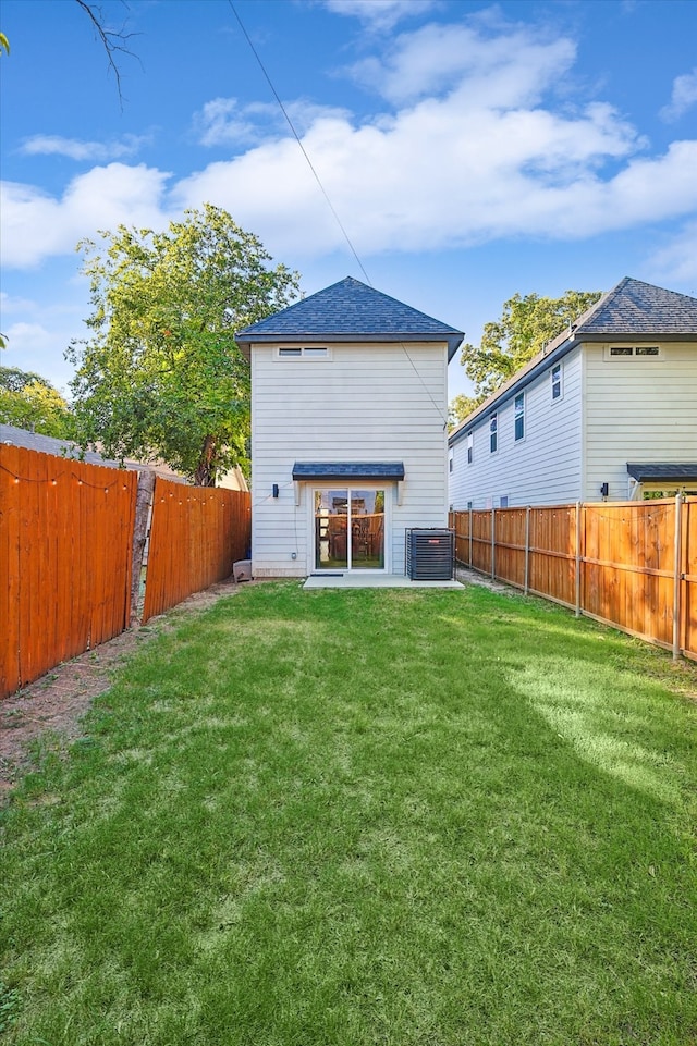 rear view of house featuring cooling unit and a lawn