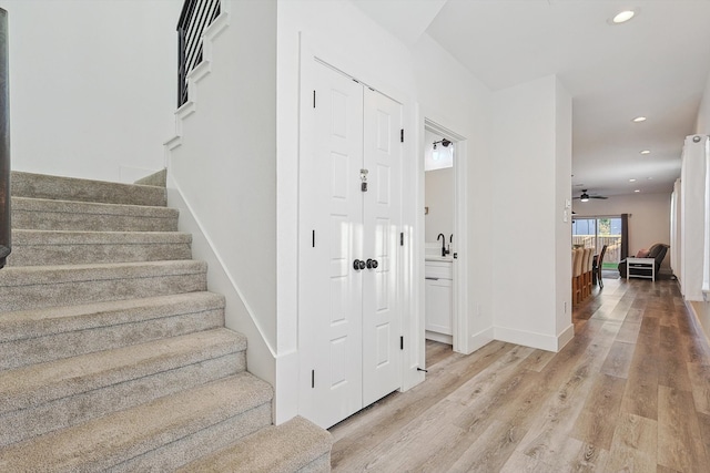 stairs featuring sink, hardwood / wood-style flooring, and ceiling fan