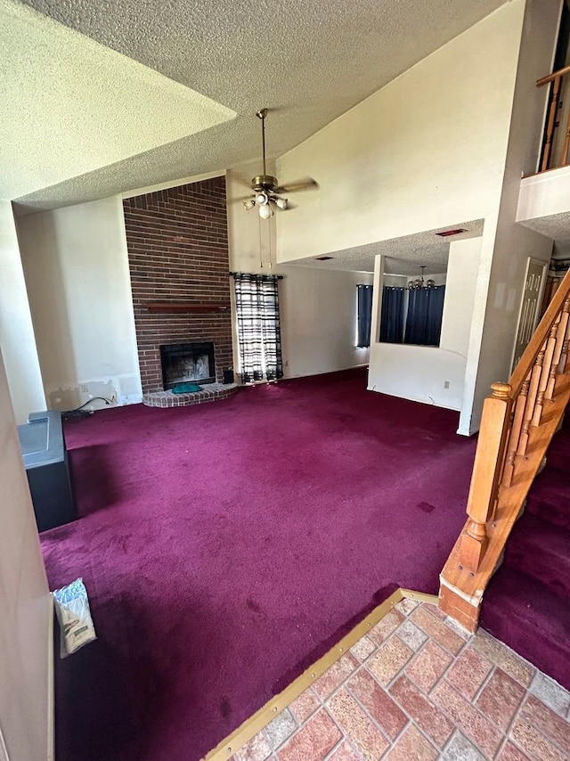 unfurnished living room with ceiling fan, a textured ceiling, a fireplace, and carpet