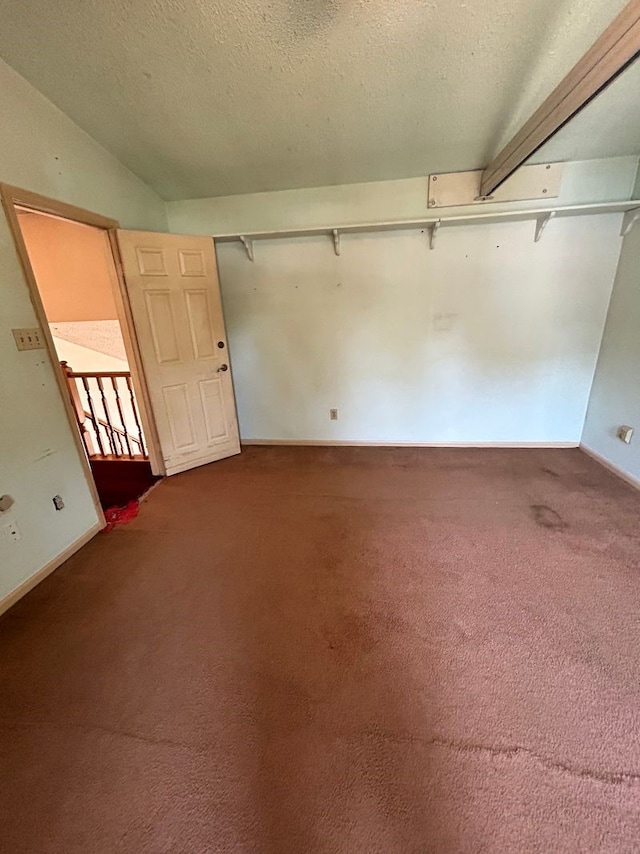 carpeted empty room with a textured ceiling and lofted ceiling