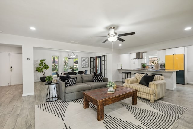 living room featuring ceiling fan, sink, and light hardwood / wood-style floors