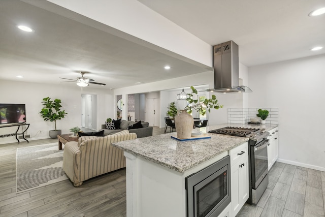 kitchen with stainless steel appliances, white cabinetry, extractor fan, and wood-type flooring