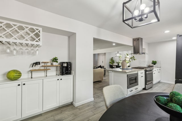 kitchen with appliances with stainless steel finishes, ventilation hood, pendant lighting, light hardwood / wood-style floors, and white cabinetry