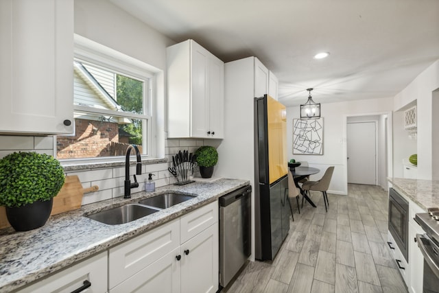 kitchen featuring backsplash, light stone countertops, appliances with stainless steel finishes, light hardwood / wood-style floors, and white cabinetry