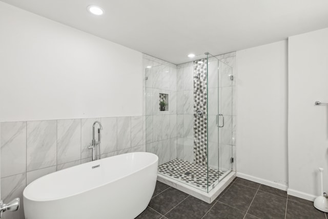 bathroom with tile patterned floors, tile walls, and shower with separate bathtub