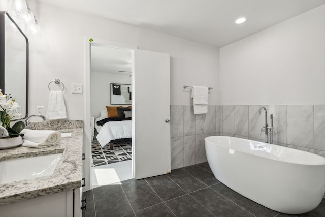 bathroom with tile patterned floors, a bathing tub, vanity, and tile walls