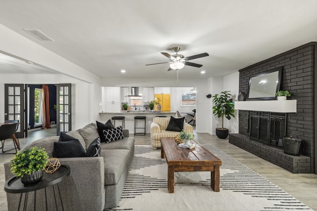 living room with ceiling fan, light hardwood / wood-style floors, a fireplace, and a wealth of natural light