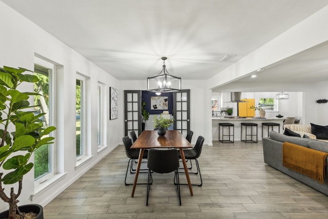 dining room with light wood-type flooring and an inviting chandelier