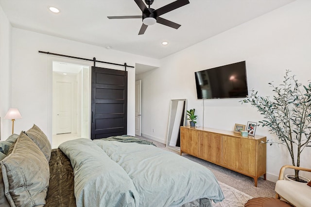 carpeted bedroom with a barn door and ceiling fan