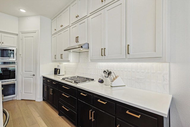 kitchen featuring stainless steel appliances, white cabinetry, light hardwood / wood-style flooring, and tasteful backsplash