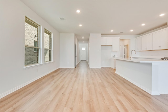 unfurnished living room with sink and light hardwood / wood-style flooring