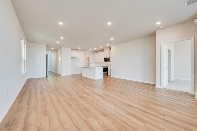 unfurnished living room with sink and light hardwood / wood-style flooring