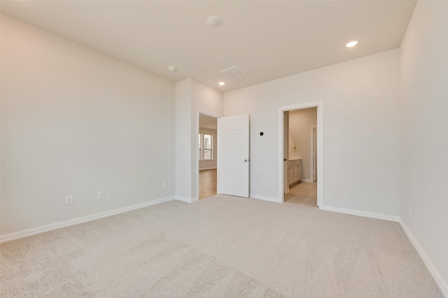 unfurnished bedroom featuring ensuite bath and light colored carpet