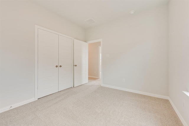 unfurnished bedroom with a closet and light carpet