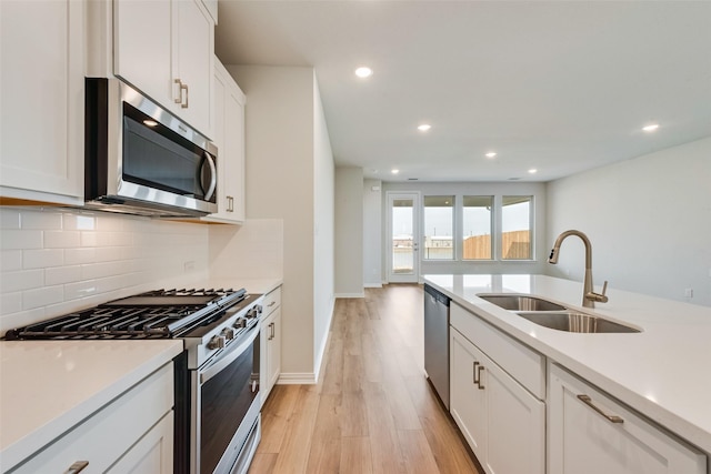 kitchen with sink, white cabinets, decorative backsplash, light hardwood / wood-style floors, and stainless steel appliances