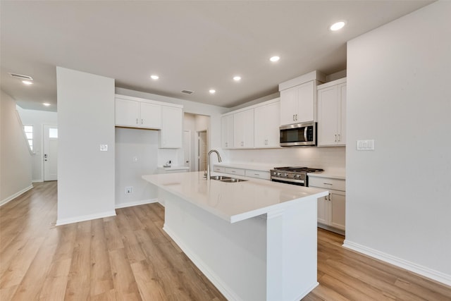 kitchen featuring appliances with stainless steel finishes, sink, a center island with sink, and white cabinets