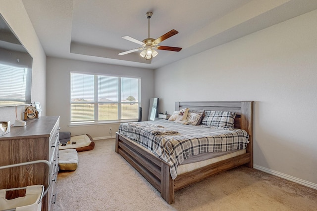 bedroom featuring ceiling fan, light colored carpet, and a raised ceiling