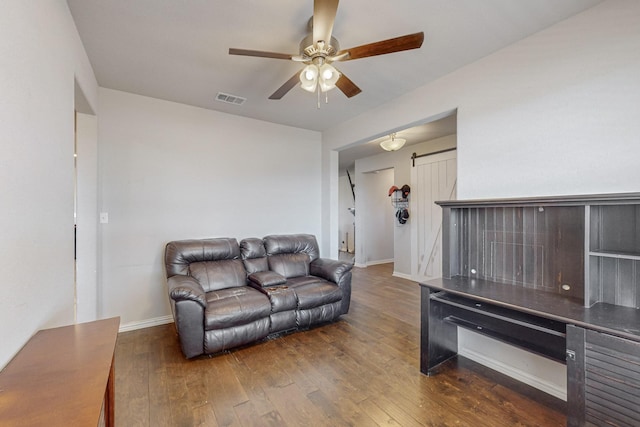 living room featuring dark hardwood / wood-style flooring, a barn door, and ceiling fan