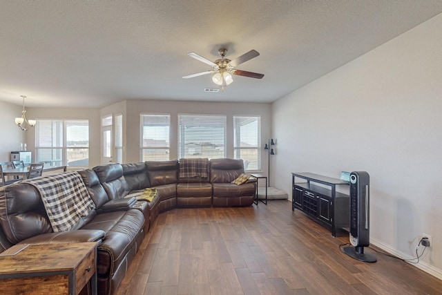 living room featuring dark hardwood / wood-style floors, ceiling fan with notable chandelier, and a textured ceiling