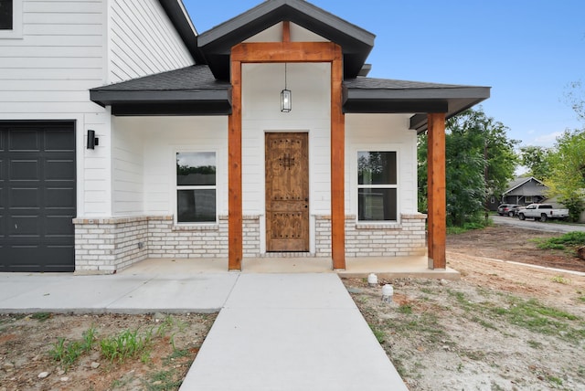 view of exterior entry with covered porch and a garage