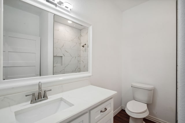 bathroom with toilet, vanity, and a tile shower