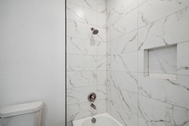 bathroom featuring tiled shower / bath and toilet