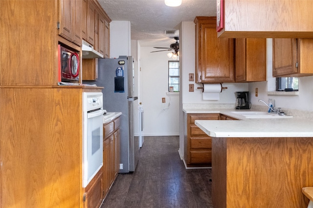 kitchen featuring oven, sink, a textured ceiling, kitchen peninsula, and dark wood-type flooring