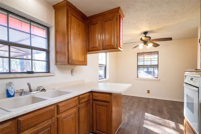 kitchen featuring sink, dark wood-type flooring, white oven, and a healthy amount of sunlight