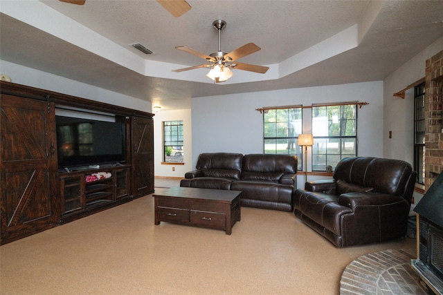 living room featuring a raised ceiling, a textured ceiling, and ceiling fan