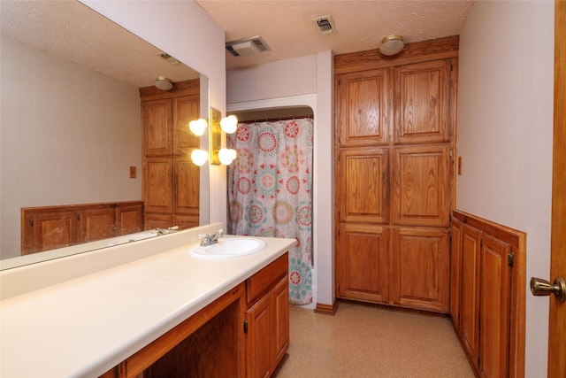 bathroom featuring vanity, a textured ceiling, and curtained shower