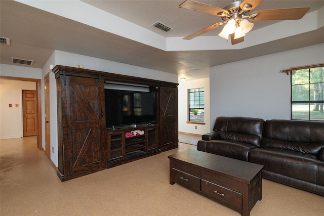 living room featuring ceiling fan, a textured ceiling, and a barn door