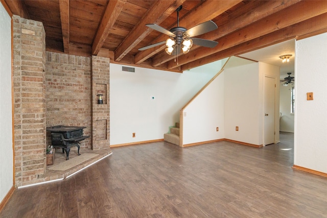 unfurnished living room with a wood stove, ceiling fan, wooden ceiling, beam ceiling, and hardwood / wood-style flooring