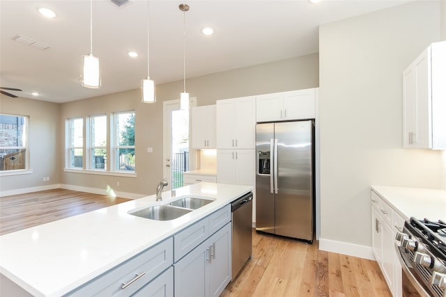 kitchen with white cabinetry, a kitchen island with sink, sink, light hardwood / wood-style floors, and stainless steel appliances