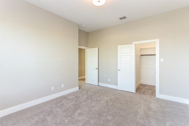 unfurnished bedroom with a closet, a spacious closet, and light colored carpet