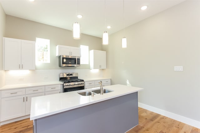 kitchen with white cabinetry, appliances with stainless steel finishes, sink, and an island with sink