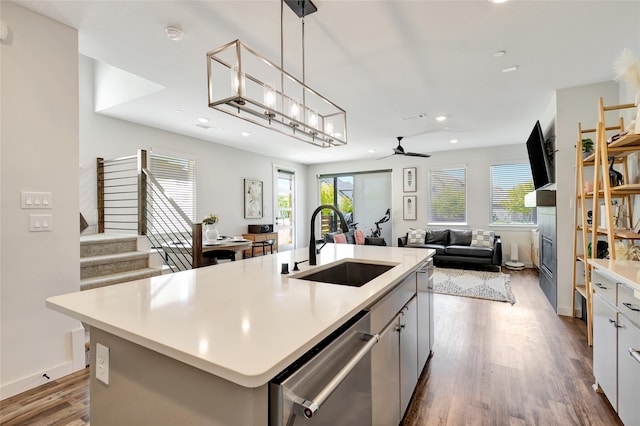 kitchen with dishwasher, a center island with sink, sink, hardwood / wood-style floors, and white cabinets