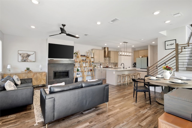 living room with light hardwood / wood-style floors, sink, a fireplace, and ceiling fan