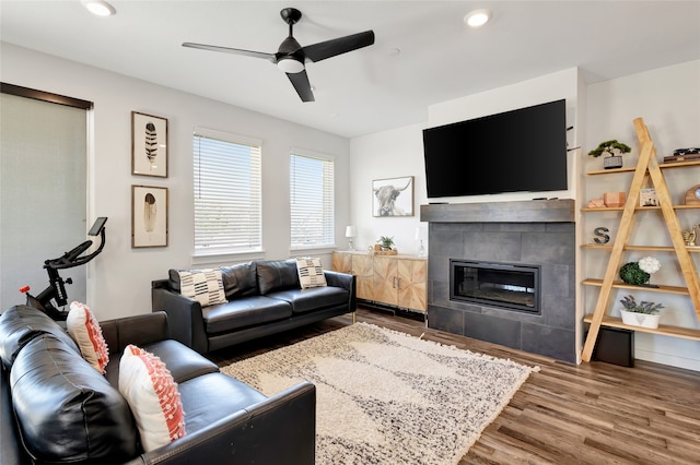 living room featuring hardwood / wood-style floors, a tile fireplace, and ceiling fan