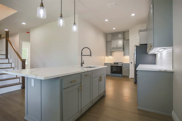 kitchen with a center island with sink, dark hardwood / wood-style flooring, stainless steel appliances, sink, and decorative light fixtures