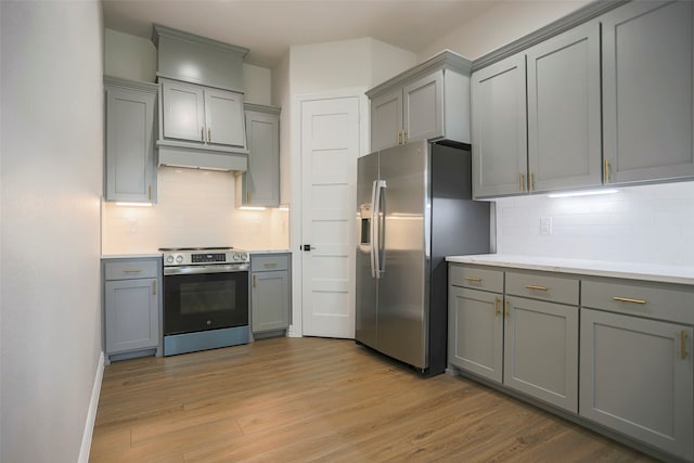 kitchen featuring gray cabinetry, backsplash, stainless steel appliances, and light wood-type flooring