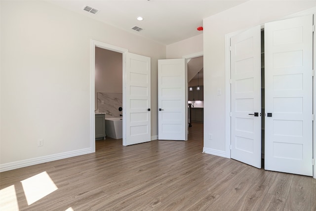 unfurnished bedroom with connected bathroom and light hardwood / wood-style flooring