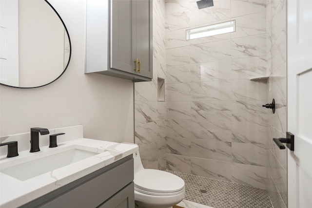 bathroom with a tile shower, toilet, and vanity