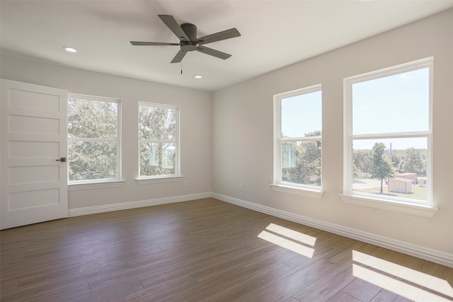 spare room with a healthy amount of sunlight, dark wood-type flooring, and ceiling fan