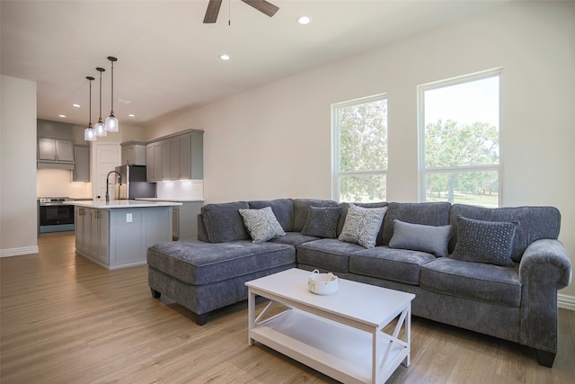 living room with light hardwood / wood-style floors, sink, and ceiling fan