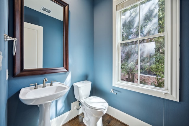 bathroom featuring toilet, wood-type flooring, and plenty of natural light