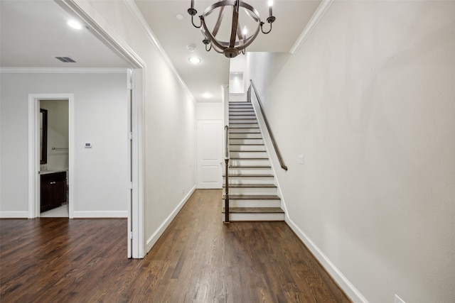 staircase with ornamental molding, an inviting chandelier, and hardwood / wood-style floors