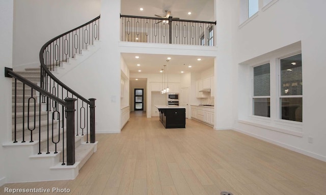 2414 Plumeria Ln, Celina, TX 75009 - interior space with light wood-style flooring, stairway, a towering ceiling, and baseboards